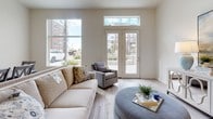 This well-designed single-floor residence offers a clean, contemporary aesthetic defined by a neutral color palette, light wood-look flooring, and an abundance of natural light. The open-concept kitchen is a functional highlight, featuring crisp white cabinetry extending to the ceiling, a soft blue subway tile backsplash, stainless steel appliances including a refrigerator, range, and microwave, and a peninsula with bar seating — ideal for casual dining or meal prep. Adjacent to the kitchen, a dedicated dining area accommodates a full-sized table beneath a classic chandelier, with a large window framing views of the surrounding community. The living room is bright and airy, with oversized windows and French doors that open directly to an outdoor patio, seamlessly blending indoor and outdoor living. Two bedrooms offer plush carpeting, generous windows with exterior views, and a calm, restful ambiance. The primary bathroom features an extended vanity with white countertops, wood-look flooring, a glass-enclosed shower, and access to a walk-in closet. A second full bathroom includes a tiled soaking tub and shower combination with brushed nickel fixtures. Throughout, the space maintains a cohesive, modern sensibility with high ceilings and thoughtful attention to detail.