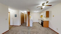 Located at 11581 Raven St NW in Coon Rapids, Minnesota, this two-bedroom, one-bathroom unit offers a practical and comfortable single-floor layout. The living area is carpeted and features a sliding glass door with vertical blinds that allows natural light to fill the space, along with a wall-mounted air conditioning unit for year-round comfort. Baseboard heating runs throughout the unit, providing consistent warmth during Minnesota winters.

The kitchen is laid out in a galley style with white cabinetry accented by warm wood trim, a coil-top electric range, refrigerator, black dishwasher, and a stainless steel sink. Tile-style flooring and a ceiling fan with light fixture complete the kitchen and adjacent entrance area.

Both bedrooms are carpeted and feature windows with blinds that bring in natural light and views of the surrounding neighborhood. The primary bedroom is generously sized and notably includes two closets plus an additional door, offering ample storage. The second bedroom also features baseboard heating and a window.

The bathroom is well-appointed with tile-style flooring, a wood-toned vanity with a single sink, a full tub-shower combination, and a large mirror. Textured ceilings are consistent throughout the unit, contributing to its classic residential character.