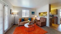 This single-floor residence is organized into several distinct functional areas that connect in a logical, accessible layout. The living room serves as the central gathering space, featuring a combination of carpet and hardwood-style flooring, a large front-facing window, and a glass-paneled entry door that invites natural light into the room. A pass-through opening in the wall connects the living area to the kitchen, maintaining an open feel while defining each zone.

The galley-style kitchen is efficiently arranged with warm wood cabinetry extending to the ceiling, granite-look countertops, and hardwood-style flooring. It accommodates a full-size refrigerator, an electric range, and a sink, providing all essential cooking amenities within a compact footprint.

Adjacent to the living room, a dedicated dining area features hardwood-style flooring and a ceiling fan, offering a comfortable space for meals. The bedroom is generously sized with plush carpet, multiple windows dressed with blinds, and direct access to a full bathroom that includes built-in shelving for storage. Overall, the unit presents a cohesive, functional layout with consistent neutral-toned walls throughout.