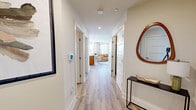 This model unit in Ellicott City, Maryland, offers a thoughtfully designed single-floor layout with one bedroom, three bathrooms, and a comfortable sense of space throughout. Light wood-look flooring runs through the entryway and hallways, creating a clean, cohesive aesthetic from the moment you enter. The welcoming entry hall leads past multiple doors to the main living areas, with recessed lighting overhead enhancing the bright, neutral palette.

The kitchen is well-equipped with warm wood cabinetry, granite countertops, stainless steel appliances, a subway tile backsplash, and a central island with a sink — all illuminated by track lighting and a large window. It opens toward the living room, which features sliding glass doors that invite natural light and provide outdoor access.

The primary bedroom offers carpeted flooring, multiple windows for ample natural light, and access to a spacious walk-in closet outfitted with wire shelving systems. The bathrooms are finished with granite countertops, wood cabinetry, large mirrors, and tile-surround glass-door showers. Throughout, the design maintains a consistent modern aesthetic with clean lines, neutral tones, and quality finishes.