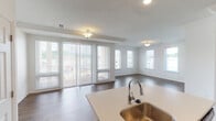 This single-floor residence offers a thoughtfully designed open-concept layout that seamlessly connects the kitchen, dining, and living areas. The expansive living space is bathed in natural light, courtesy of large sliding glass doors and multiple windows that frame outdoor views, all complemented by rich hardwood-style flooring and a tray ceiling detail.

The kitchen is a standout feature, showcasing dark espresso cabinetry with brushed nickel hardware, crisp white countertops, a large center island with an integrated sink, and a full suite of stainless steel appliances including a range, over-the-range microwave, and refrigerator. Crown molding and recessed lighting add an elegant finishing touch to this functional space.

The bedrooms are generously sized, featuring plush carpeting and ample natural light from multiple windows. The primary bedroom benefits from dual closets, providing excellent storage capacity. The primary bathroom is well-appointed with a dual-sink vanity, dark cabinetry, white countertops, and hardwood-style flooring. A secondary bathroom features a tub-shower combination, dark vanity cabinetry, and matching flooring. Throughout, the residence maintains a clean, neutral palette that creates a bright and welcoming ambiance.