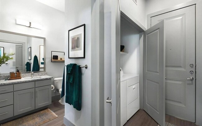 Entryway View Showing Bathroom with Granite Countertop and In-Unit Laundry Closet - Rhythm