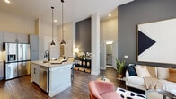 Located at 700 Corporate Center Dr in Raleigh, NC, this single-floor residence offers a thoughtfully designed open-concept layout with soaring ceilings and upscale finishes throughout. The kitchen is a standout feature, equipped with gray shaker-style cabinetry, granite countertops, stainless steel appliances including a French door refrigerator, a subway tile backsplash, and a central island with pendant lighting and bar seating — ideal for casual dining or entertaining. The living area flows seamlessly from the kitchen, featuring wide-plank hardwood-style flooring, a bold accent wall, and floor-to-ceiling windows with access to a private balcony, allowing generous natural light and outdoor views. The primary bedroom is a serene retreat, while a secondary bedroom offers its own window with exterior views. Two bathrooms serve the residence: a full primary bath featuring a dual-sink granite vanity with gray cabinetry, a glass-enclosed walk-in shower, and hardwood-style flooring; and a secondary bath with a granite vanity and a tub-shower combination with marble-style tile surround. An in-unit washer completes the practical amenities. The overall ambiance is contemporary and refined, blending neutral tones with modern fixtures for a polished, move-in-ready feel.