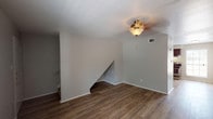 This two-story townhome features 2 bedrooms and 1.5 bathrooms, thoughtfully laid out across two floors. The main level showcases rich wood-style plank flooring throughout the living area, which is bright and open with a ceiling fan overhead and a staircase leading to the upper level. Adjacent to the living space, the kitchen is well-appointed with dark espresso cabinetry, granite-style countertops, stainless steel appliances including an electric range, an under-cabinet range hood, and a window that brings in natural light. A pantry provides additional storage. A convenient half bathroom with wood-style flooring is also located on the main level. Upstairs, both bedrooms are carpeted and feature ceiling fans, windows with blinds for natural light and privacy, and ample wall space. The full bathroom on the upper level includes a dark-framed vanity mirror, granite-style countertops, dark cabinetry, and a well-lit vanity area. The layout is practical and efficient, with neutral tones throughout creating a clean, move-in-ready aesthetic. The two-story design provides a clear separation between living and sleeping areas, enhancing the overall livability of the home.