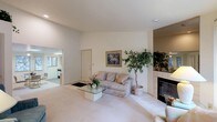 Located at 8424 N Nevada St in Spokane, Washington, this single-floor home offers a well-organized layout with a variety of comfortable living spaces. The expansive main living area is a standout feature, centered around a tiled fireplace and accented by large vertical-blind windows that invite abundant natural light and views of the surrounding greenery. Soft neutral carpeting and light-toned walls create a warm, cohesive atmosphere throughout. A secondary sitting room provides additional living space, featuring its own large sliding glass door and serene outdoor views, making it ideal for relaxation or casual gatherings. The kitchen is well-equipped with ample light wood cabinetry, a full suite of appliances including a dishwasher, range, and refrigerator, and an adjoining dining area. The bedrooms are generously sized, each with carpeted floors and windows overlooking mature trees. One bedroom features an en-suite bathroom with a light wood vanity and tile flooring. An additional full bathroom includes a soaking tub, patterned tile floors, and matching vanity cabinetry. A cozy bonus room with wicker seating offers versatile use as a den or reading nook. This home presents a calm, functional, and inviting living environment throughout.