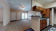 This well-appointed single-floor residence offers three bedrooms and two full bathrooms within a thoughtfully designed open layout. The living room serves as the heart of the home, featuring vaulted ceilings, crown molding, and a ceiling fan that enhance the sense of spaciousness. Soft carpeting runs throughout the living and bedroom areas, while dark hardwood-style flooring defines the kitchen and dining spaces. Natural light filters in through a glass door with sheer curtains, adding warmth to the living area.

The kitchen is efficiently laid out with warm wood cabinetry, dark granite-style countertops, and black appliances, including a refrigerator, microwave, and range. A peninsula breakfast bar connects the kitchen to the dining area, making it ideal for casual dining or entertaining.

The bedrooms are carpeted and offer comfortable proportions, each with window treatments that allow for natural light control. Both bathrooms feature wood-toned vanities with ample storage and tub-shower combinations finished with white tile surrounds. Dark hardwood-style flooring runs through both bathrooms, providing a cohesive and easy-to-maintain finish throughout the wet areas of the home.