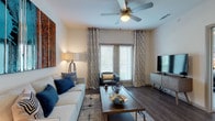This single-story, one-bedroom, one-bathroom residence offers a thoughtfully designed open-concept layout that maximizes functionality and comfort. The living area features rich wood-look flooring, a ceiling fan, and sliding glass doors that invite natural light while providing outdoor access. Neutral walls serve as a versatile backdrop, complemented by ample space for seating and entertainment.

The kitchen is a standout feature, showcasing a large granite-topped island with bar seating, illuminated by pendant lighting overhead. Two-tone cabinetry pairs light upper cabinets with darker lower units, while stainless steel appliances—including a refrigerator, range, and microwave—complete the modern aesthetic. A mosaic tile backsplash adds a refined decorative touch.

The bedroom is generously proportioned, with plush carpeting underfoot, a ceiling fan, and large windows framing greenery-filled outdoor views. The room comfortably accommodates substantial furniture and benefits from abundant natural light.

The bathroom features dark wood cabinetry, granite countertops, a large framed mirror, wood-look flooring, and a shower-tub combination. The overall ambiance throughout the residence is contemporary and cohesive, with consistent finishes that create a polished, move-in-ready environment.