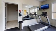 Located at 255 E Grand Ave in Rahway, NJ, this fitness center offers a well-organized and fully equipped workout space designed to support a range of exercise routines. The room features durable rubber flooring throughout, providing a safe and practical surface for all types of physical activity.

Cardio equipment is a highlight of the space, with multiple treadmills and an elliptical trainer positioned near large windows fitted with blinds, allowing natural light to fill the area while offering views to the outside. A cycling bike provides an additional low-impact cardio option. For strength training, the center includes a Star Trac Instinct multi-functional cable machine accompanied by a weight bench, offering versatile resistance training capabilities.

A full-length wall mirror expands the sense of space and allows users to monitor their form during workouts. A wall-mounted television adds an entertainment element for those engaged in longer cardio sessions. Motivational wall lettering reading "Don't Quit" adds an energetic touch to the room's clean, white-painted interior.

The fitness center is accessed through a dedicated entrance and includes a nearby restroom for convenience. Cleaning supplies are readily available, reflecting attention to hygiene and upkeep. The space is bright, functional, and thoughtfully arranged to accommodate multiple users simultaneously.