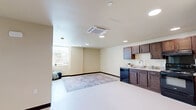 This 2-bedroom, 1-bathroom residence is thoughtfully laid out on a single floor, offering a functional and comfortable living environment. The kitchen is a standout feature, equipped with rich dark-stained wood cabinetry, light countertops, a double-basin sink, and black appliances including a range, dishwasher, and refrigerator. Recessed lighting illuminates the space, which opens to the main living area with easy-care flooring throughout.

Both bedrooms are carpeted and feature ceiling fans with lighting, providing a cozy and well-ventilated retreat. The primary bedroom benefits from multiple windows that invite natural light and outdoor views, while the second bedroom also includes window access to natural light. One bedroom includes a spacious walk-in closet with wire shelving and hanging rods, while the other features a sliding-door closet for additional storage.

The bathroom is cleanly designed with a dark wood vanity, light countertop, a large mirror with overhead lighting, and a shower-tub combination. An in-unit laundry area houses a full-size washer and dryer alongside the electrical panel, adding everyday convenience. Dark wood baseboards throughout provide a consistent, polished finishing detail across the entire residence.