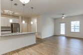 Located at 158 S Davis Rd in LaGrange, Georgia, this single-story residence offers a clean, modern interior designed for comfortable everyday living. The open-concept living and dining area flows seamlessly into the kitchen, unified by warm hardwood-style flooring throughout. Pendant lighting hangs above a granite-topped breakfast bar, anchoring the space and creating a natural gathering point between the kitchen and living areas. A ceiling fan and large glass door in the living room allow natural light to fill the space while providing outdoor access.

The kitchen is well-appointed with white shaker-style cabinetry, granite countertops, and a full suite of stainless steel appliances including a refrigerator, range, and over-the-range microwave. Track lighting illuminates the workspace efficiently.

The bedrooms feature neutral carpet, white panel doors, and windows fitted with horizontal blinds that admit natural light. Each room offers a calm, understated atmosphere well-suited for rest or use as a home office.

The bathroom includes a walk-in shower enclosed by a framed glass door, complemented by hardwood-style flooring. Throughout the home, crisp white walls and consistent finishes create a cohesive, move-in-ready aesthetic.