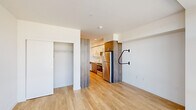 Located in Portland's vibrant West End neighborhood, this efficiently designed single-floor unit at 1670 SW Alder St offers a thoughtful layout across a living room, kitchen, and bathroom. The living area is anchored by a large floor-to-ceiling window that floods the space with natural light and frames views of the surrounding Portland cityscape. Light-toned hardwood flooring runs throughout, lending warmth and visual continuity to the open layout. A closet with built-in shelving provides practical storage within the living space.

The kitchen is designed with functionality in mind, featuring a clean combination of white upper cabinetry and wood-toned lower cabinets, white quartz countertops, and a full suite of stainless steel appliances including a range with electric cooktop, over-the-range microwave, and refrigerator. A single-basin stainless steel sink and additional open wood shelving round out the kitchen's storage options.

The bathroom includes a walk-in shower with clean white surround and chrome fixtures. Throughout the unit, the design aesthetic is contemporary and minimalist, with crisp white walls, recessed lighting, and a neutral palette that maximizes the sense of space. This unit offers a practical and modern urban living experience in the heart of Portland.