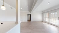 This single-floor residence offers a thoughtfully designed open layout that connects the main living areas seamlessly. The living room is a standout space, featuring a classic white-mantled fireplace framed by built-in shelving and large windows with plantation shutters that allow natural light to pour in. French doors lead to an outdoor area, adding to the bright, airy feel of the room. Crown molding and a tray ceiling add architectural refinement throughout.

The kitchen is equipped with a peninsula breakfast bar topped with light quartz countertops, pendant lighting, white cabinetry, and black appliances. An integrated sink and open sightlines to the living and dining areas make it ideal for everyday functionality.

The bedroom is generously proportioned, featuring a ceiling fan, a wide window with natural light, and direct access to a walk-in closet. Light-toned hardwood-style flooring runs consistently across all rooms, lending a cohesive and clean aesthetic.

The bathroom is well-finished, showcasing a tiled tub-shower combo with grey subway tile and a decorative mosaic border, a white vanity with quartz countertop, and warm wood-style flooring. The overall design palette—neutral whites and soft greys—creates a calm, modern atmosphere throughout this inviting space.