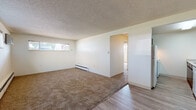 Located at 2601 23rd Ave in Greeley, Colorado, this single-floor unit offers a straightforward and functional layout ideal for comfortable everyday living. The living area is generously sized, featuring warm neutral carpet, crisp white walls, and a textured ceiling. Horizontal strip windows allow natural light to filter in while baseboard heating units run along the walls, ensuring warmth throughout. The transition between the living space and entryway is marked by durable wood-look laminate flooring, providing a clean contrast to the carpeted areas. The bedroom spaces are bright and well-proportioned, each with carpet flooring, baseboard heat, and windows that bring in natural light from the surrounding neighborhood. The galley-style kitchen is efficiently designed with dark wood cabinetry on both sides, light granite-look countertops, a stainless steel sink, and white appliances including a range, refrigerator, and dishwasher. Light laminate flooring runs through the kitchen, making it easy to maintain. The bathroom features a full tub and shower combo with clean white square tile surround, chrome fixtures, and a grab bar for added accessibility. Overall, the space presents a clean, move-in-ready environment with consistent finishes throughout.