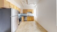 Located at 413 Pierce St in Sioux City, Iowa, this one-bedroom, one-bathroom unit offers an efficient and well-designed single-floor layout. The space showcases an industrial-inspired aesthetic throughout, highlighted by polished concrete floors, exposed ductwork, and track lighting that run across the ceilings, lending an urban loft character to the interior.

The kitchen is a standout feature, outfitted with light wood cabinetry, gray countertops, and a full suite of stainless steel appliances including a refrigerator, electric range, over-the-range microwave, and dishwasher. A window brings natural light into the kitchen area, enhancing its open and functional feel.

The bedroom offers a comfortable footprint with elevated ceilings, a ceiling fan, and direct access to both a dedicated closet and the full bathroom. The closet provides practical built-in shelving, while the clean white walls create a bright, neutral backdrop throughout.

The bathroom features a full tub-shower combination with modern brushed nickel fixtures set against crisp white surfaces. The corridor connecting the rooms is accented by the same exposed ductwork found throughout, reinforcing the unit's cohesive industrial design language. Overall, this unit delivers a clean, modern living environment with distinctive architectural character.