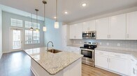This well-appointed one-bedroom, one-bathroom residence at 700 City View Loop in Midlothian, VA offers a thoughtfully designed open-concept layout that maximizes its efficient footprint. The combined kitchen and living area serves as the heart of the home, showcasing crisp white shaker cabinetry, granite countertops, a subway tile backsplash, and a full suite of stainless steel appliances including a range, built-in microwave, and refrigerator. A central kitchen island with an undermount sink and elegant pendant lighting above adds both functionality and style. Light wood-tone flooring flows throughout the main living areas, complementing the soft, neutral color palette. The living area benefits from generous natural light through large windows and a glass door that opens to an outdoor view, with a ceiling fan overhead adding comfort. The bedroom offers plush carpeting, a ceiling fan, and a bright window, creating a calm and comfortable retreat. A dedicated closet provides practical storage. The bathroom features granite countertops on white cabinetry, a tiled tub-shower combo, and wood-look flooring that ties seamlessly to the rest of the home. Clean lines and modern finishes throughout give this residence a fresh, contemporary feel.