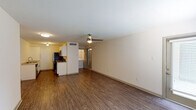 This single-story unit in Baton Rouge, Louisiana offers a practical and comfortable layout designed to maximize functionality. The open living area is finished with rich, dark wood-style flooring that extends throughout the unit, creating a cohesive and polished look. A ceiling fan with integrated lighting serves the main living space, while a flush-mount fixture provides additional illumination. Natural light filters in through a windowed exterior door, adding brightness to the living area.

The galley-style kitchen is well-equipped with stainless steel appliances, including a refrigerator, electric range, microwave, and dishwasher. White cabinetry with brushed hardware lines both sides of the kitchen, complemented by light granite-style countertops and a stainless steel sink, offering ample storage and workspace.

A dedicated laundry area is conveniently located within the unit, visible from the main living space. The bathroom features a full tub-shower combination with built-in shelving, a toilet, and a vanity with matching granite-style countertops. The consistent wood-style flooring carries into the bathroom, reinforcing the unit's unified aesthetic. The layout flows efficiently, making practical use of the available square footage throughout.