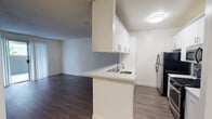 Located at 11657 Oxnard St in the North Hollywood neighborhood of Los Angeles, Unit 214 is a thoughtfully designed single-floor residence that blends functionality with clean, modern aesthetics. The open-concept layout connects the kitchen and living area seamlessly, creating an inviting and versatile space throughout.

The kitchen is efficiently designed with crisp white cabinetry, light countertops, a mosaic tile backsplash, and stainless steel appliances including a gas range, microwave, and refrigerator. A peninsula with a built-in sink separates the kitchen from the living area while maintaining an open sightline, ideal for both cooking and entertaining.

The living area is bright and airy, featuring dark hardwood-style flooring that runs throughout and a sliding glass door that opens to a private balcony, allowing natural light to fill the space and offering an outdoor retreat. Vertical blinds provide privacy while softening the incoming light.

The bathroom is well-appointed with a white vanity, a large mirror, tiled tub surround, and warm accent lighting, providing a clean and functional space.

Throughout the unit, textured ceilings, neutral walls, and consistent flooring create a cohesive and polished look, making this North Hollywood residence a practical and comfortable urban home.