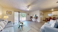 Located at 1521 Mahaffey Cir in Lakeland, Florida, this single-story home offers a well-organized layout with distinct living, dining, kitchen, and sleeping areas. The living room serves as a central gathering space, featuring wood-look flooring, a ceiling fan with light fixture, and a textured ceiling. Large sliding glass doors flood the room with natural light and provide direct views of the lush, green outdoor surroundings, with access to a patio area. A separate sitting area adjacent to the living room offers additional flexible space, also finished with wood-look flooring and wainscoting detail along the walls.

The kitchen is designed with light oak cabinetry, ample counter space, and a convenient pass-through window that opens directly to the dining area, promoting an open and connected feel. The dedicated dining room comfortably accommodates a full-sized table and is finished with matching wood-look flooring and a textured ceiling.

The bedrooms are carpeted for comfort, offering a quieter, softer atmosphere. The bathroom is finished in white with a single vanity, a large mirror, and a shower-tub combination. Throughout the home, neutral tones and consistent finishes contribute to a cohesive and inviting ambiance.