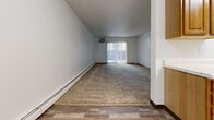 Located at 215 E Arbor Ave in Bismarck, North Dakota, this two-bedroom unit offers a practical and well-organized single-floor layout. The space features a mix of wood-look hard flooring in the entryway and living areas, transitioning to soft, neutral-toned carpet in the bedrooms and main living room.

The living room is a generous, elongated space bathed in natural light from a large sliding glass door fitted with vertical blinds, creating a bright and open atmosphere. A wall-mounted air conditioning unit and baseboard heating ensure year-round comfort throughout the home.

The kitchen is efficiently designed and positioned adjacent to the living area, equipped with a white range and ample cabinetry. A hallway connects the main living areas to the bedrooms, providing a clear and functional flow through the unit.

Both bedrooms are carpeted and feature white walls, warm wood-trimmed windows with horizontal blinds, and baseboard heating. The primary bedroom is a well-proportioned room offering comfortable space for furnishings. The second bedroom is cozy and versatile. A dedicated closet provides convenient storage. Clean white walls, wood baseboards, and consistent finishes throughout give the unit a neat, uniform appearance.