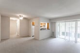 This single-floor residence is designed with a practical, well-organized layout that maximizes usability across its living spaces. The open living area is generously sized, finished with neutral-toned wall-to-wall carpeting, and anchored by a ceiling fan fixture. A partition wall with a pass-through window connects the living space to the kitchen, maintaining an open feel while defining each area. Sliding glass doors fitted with vertical blinds lead to an outdoor space, bringing in natural light and providing exterior access.

The kitchen is well-equipped, featuring warm oak cabinetry with ample upper and lower storage, dark granite-style countertops, white appliances including a gas range, dishwasher, and refrigerator, and a window that allows natural light. The tile flooring adds practicality to this workspace.

The bedrooms are carpeted and bright, each receiving natural light through windows with blinds. At least one bedroom includes a walk-in closet, offering notable storage capacity. A hallway connects the sleeping areas to the rest of the unit.

The bathroom includes a single-sink vanity with oak cabinetry, a large mirror with overhead lighting, and a full tub-shower combination with white tile surround. Tile flooring completes the space with a clean, functional finish.