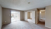 This single-floor, 3-bedroom, 2-bathroom unit offers a practical and functional layout designed to maximize everyday comfort. The living area is generously sized, featuring soft carpeting, neutral taupe-toned walls, and a sliding glass door fitted with vertical blinds that allows natural light to pour in while providing access to the outdoors. A textured ceiling runs throughout the main living spaces, adding subtle dimension overhead.

The kitchen is positioned adjacent to the living and dining area, connected via a pass-through counter with dark laminate countertops. White cabinetry, a white electric range, refrigerator, and sink are all included, and the kitchen features easy-to-maintain light wood-look vinyl flooring. This same flooring carries into both bathrooms, each of which includes a tub-shower combo, toilet, and overhead cabinetry for storage.

All three bedrooms are carpeted and feature neutral walls with windows dressed in horizontal blinds, providing natural light and outdoor views. The primary bedroom includes a ceiling fan with integrated lighting. The floor plan flows efficiently, with bedrooms positioned off a central hallway for added privacy. Overall, the unit presents a clean, move-in-ready environment with a consistent, understated aesthetic throughout.