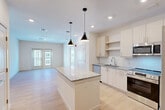 This well-appointed 2-bedroom, 2-bathroom residence in Waltham, MA offers a thoughtfully designed single-floor layout with a bright, open-concept living space. The combined dining room, kitchen, and living area forms the heart of the home, anchored by a granite-topped center island with stylish pendant lighting overhead. The kitchen is equipped with stainless steel appliances—including a French door refrigerator, electric range, built-in microwave, and dishwasher—complemented by light wood cabinetry, a subway tile backsplash, and granite countertops. Light hardwood flooring flows seamlessly throughout the entire residence, enhancing its clean, contemporary aesthetic. The living area is bathed in natural light courtesy of large double doors that open to an outdoor view. Both bedrooms are well-sized and serene, with large windows framing exterior views. The primary bathroom features a granite vanity, a tiled soaking tub and shower combo, and built-in shelving. The second bathroom includes a glass-enclosed shower and granite countertop vanity. Additional conveniences include three closets, a pantry, in-unit laundry, and a utility room, ensuring ample storage and functionality throughout.