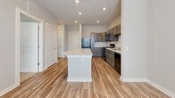 Located at 565 Cobb Pkwy S in Marietta, Georgia, this one-bedroom, one-bathroom unit offers a thoughtfully designed layout across a single floor. The open-concept kitchen serves as the heart of the space, featuring gray-toned cabinetry with brushed hardware, light stone countertops, black appliances including a refrigerator, range, microwave, and dishwasher, and a freestanding island that provides additional prep and dining space. Wood-look plank flooring runs throughout the main living and kitchen areas, adding warmth and durability.

The generously sized bedroom is finished with soft carpeting and benefits from a large window that brings in natural light. A ceiling fan adds comfort and functionality. The room connects to a dedicated closet, providing ample storage.

The bathroom is clean and modern in design, featuring wood-look flooring that complements the rest of the unit, a walk-in shower with a frameless sliding glass enclosure, a toilet, and a vanity with dark wood cabinetry, a single sink, and a large mirror. Recessed lighting and neutral gray walls create a bright, calm atmosphere throughout the unit. The overall aesthetic is contemporary and cohesive, with a neutral palette that offers a versatile backdrop for a variety of interior styles.