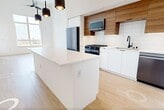 This contemporary two-story residence at 3585 Aero Ct in San Diego, CA offers 1,640 square feet of thoughtfully designed living space across two floors. The main level spans 1,110 square feet and features an open-concept living area with soaring ceilings, light wood-tone flooring, and a modern kitchen equipped with stainless steel appliances, a gas range, built-in microwave, dishwasher, white lower cabinetry, warm wood upper cabinets, and a white tile backsplash with a matte black faucet. The upper level covers 530 square feet and houses the two bedrooms, each featuring large windows that invite abundant natural light and offer views of the San Diego skyline and surrounding neighborhood. The primary bedroom measures 200 square feet and is served by a sleek en-suite bathroom with rich wood-grain cabinetry, a backlit vanity mirror, and white quartz countertops. A second full bathroom features a soaking tub with large-format tile surround and matte black fixtures. Both bedrooms include dedicated walk-in closets with multi-tier hanging rods. The unit is completed by a private balcony with city views, ceiling fans, and two staircases for convenient access between floors.