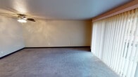 Located in Federal Way, Washington, this single-floor unit at 30823 18th Ave S offers a well-organized layout with comfortable living spaces throughout. The living room is generously sized, featuring soft wall-to-wall carpeting, warm neutral-toned walls, and a ceiling fan with a light fixture. A large sliding glass door with vertical blinds fills the room with natural light and provides outdoor views, while a fireplace adds a cozy focal point to the space.

The kitchen is thoughtfully designed with white shaker-style cabinetry, a stainless steel range, and a refrigerator. A peninsula with a built-in sink and countertop overhang provides additional prep space and a casual dining option. Wood-look flooring and recessed lighting complete the kitchen's clean, functional aesthetic.

The bedroom is a quiet, carpeted retreat with a window that allows in natural light, complemented by a baseboard heater for year-round comfort. The bathroom features a full tub and shower combination with chrome fixtures. A dedicated in-unit laundry closet houses a full-size washer and dryer with overhead shelving for storage. The unit also includes an electrical panel conveniently located near the kitchen area.