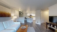 Located in Bellevue, WA, this 2-bedroom, 1-bathroom residence offers a thoughtfully designed single-level layout with a neutral color palette and dark hardwood-style flooring throughout the main living areas. The open-concept great room seamlessly connects the living room, dining area, and kitchen, creating a spacious and cohesive environment. The living room is anchored by a tile-surround fireplace with a classic white mantel and features crown molding, a ceiling fan, and a sliding glass door that opens to a private balcony with outdoor views. The kitchen is well-equipped with white shaker cabinetry, stainless steel appliances including a refrigerator, range, and microwave, quartz countertops, a deep single-basin sink, track lighting, and a large peninsula island with bar seating. A pantry and in-unit laundry area add functional convenience. The full bathroom features a wide vanity with white cabinetry, a quartz countertop, and a full soaking tub with shower. Both bedrooms are carpeted and receive natural light through large windows with views of the surrounding neighborhood. Four closets throughout the residence provide ample storage. The home is completed by a hallway connecting all rooms for an efficient and comfortable flow.