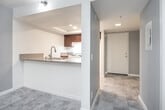 Located at 610 N Garfield St in Santa Ana, CA, this two-bedroom, one-bathroom unit offers a spacious and practical single-floor layout. The kitchen is well-appointed with rich dark wood cabinetry, granite-style countertops, a double stainless steel sink, and a gas range. A tray ceiling with recessed lighting adds a refined architectural touch, while the open pass-through counter connects seamlessly to the living area, which features tile flooring and a large window that brings in natural light.

Both bedrooms are carpeted and neutral in tone, providing a quiet, comfortable retreat. The primary bedroom is notably expansive, offering ample room for furnishings, and includes a sliding glass door that opens directly to a private balcony. A second bedroom features mirrored sliding closet doors for convenient storage. The full bathroom is cleanly finished with tile flooring, a vanity with a white countertop, and a towel bar.

The private balcony overlooks a multi-story interior courtyard shared by the building, which features textured stucco architecture and open-air common areas with potted greenery. A hallway connects the main living spaces efficiently, and the unit includes a separate entry accessible from the balcony via a large sliding panel door.