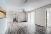 This single-story residence offers a practical and comfortable layout across four bedrooms and two bathrooms. The living room serves as the central gathering space, featuring wood-look luxury vinyl flooring, a ceiling fan with light kit, and a large sliding glass door fitted with vertical blinds that allows generous natural light to fill the room. The adjacent dining area includes a elegant chandelier overhead, continuing the same flooring for a cohesive feel. The galley-style kitchen is equipped with rich dark wood cabinetry, light countertops, a double-basin sink, and black appliances including a refrigerator, range, and dishwasher.

The bedrooms are carpeted for comfort, with several rooms featuring ceiling fans and windows that bring in outdoor views and natural light. The primary bedroom is a well-proportioned retreat with two windows. The bathrooms include vanities with dark wood cabinetry and light countertops, with one bathroom featuring a soaking tub. A dedicated laundry room with hookups and built-in shelving adds everyday convenience. Textured ceilings and clean white baseboards are consistent throughout, giving the space a uniform, move-in-ready appearance.
