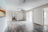 This single-story residence offers a practical and comfortable layout across four bedrooms and two bathrooms. The living room serves as the central gathering space, featuring wood-look luxury vinyl flooring, a ceiling fan with light kit, and a large sliding glass door fitted with vertical blinds that allows generous natural light to fill the room. The adjacent dining area includes a elegant chandelier overhead, continuing the same flooring for a cohesive feel. The galley-style kitchen is equipped with rich dark wood cabinetry, light countertops, a double-basin sink, and black appliances including a refrigerator, range, and dishwasher.

The bedrooms are carpeted for comfort, with several rooms featuring ceiling fans and windows that bring in outdoor views and natural light. The primary bedroom is a well-proportioned retreat with two windows. The bathrooms include vanities with dark wood cabinetry and light countertops, with one bathroom featuring a soaking tub. A dedicated laundry room with hookups and built-in shelving adds everyday convenience. Textured ceilings and clean white baseboards are consistent throughout, giving the space a uniform, move-in-ready appearance.