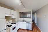Located at 14001 135A Ave NW in Edmonton, Alberta, this two-bedroom, one-bathroom home is spread across three floors, offering a practical and well-organized layout. The main living level features a combined living and dining area with warm hardwood-style flooring, neutral grey walls, and a textured ceiling. A built-in closet with sliding doors adds convenient storage to the living space. The kitchen is equipped with white cabinetry, granite-look countertops, a stainless steel dishwasher, an electric range, and a refrigerator. Track lighting illuminates the kitchen, and a pass-through window connects it to the main living area, enhancing the open feel. Natural light filters in through windows fitted with grommet-style curtains. The two bedrooms are carpeted and generously sized, each with closet space and windows overlooking the surrounding neighbourhood. The full bathroom includes a tiled tub-shower combination, a granite-top vanity, and a toilet. The unfinished basement provides additional utility and storage space, complete with exposed concrete walls, overhead ductwork, and a concrete floor. Staircases connect all three levels, making the layout easy to navigate throughout.