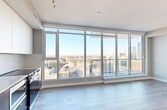 The View is a thoughtfully designed high-rise unit offering two bedrooms and one bathroom across a single floor. The open layout maximizes the use of space, with light wood-tone flooring flowing through the main living areas and creating a clean, cohesive aesthetic.

The kitchen is a standout feature, outfitted with two-tone cabinetry — white upper cabinets paired with dark lower units — and a full suite of stainless steel appliances including a refrigerator, electric range, built-in microwave, and dishwasher. A quartz countertop with a undermount sink and tile backsplash complete the polished look. Floor-to-ceiling windows at the end of the kitchen and living area flood the space with natural light and frame sweeping city views.

The primary bedroom is carpeted and features a large floor-to-ceiling window overlooking the cityscape, offering an abundance of natural light. A dedicated walk-in closet with built-in wire shelving provides generous storage. The second bedroom, also carpeted, offers a quiet and versatile space with warm-toned hardwood flooring at the entry.

The bathroom is finished with marble-look tile flooring and wall surround, a soaker tub and shower combination, and a dark-stained vanity with an undermount sink and a large mirror. A textured ceiling runs throughout, adding subtle architectural character to this bright, modern unit.