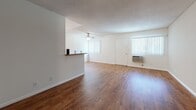 Located at 11901 176th St in Artesia, California, this single-story residence offers a functional and well-maintained layout designed for comfortable everyday living. The open-concept living and dining area is a central highlight, featuring warm hardwood-style flooring that extends throughout the main living spaces, creating a cohesive and inviting atmosphere. A textured ceiling and ceiling fan complement the room, while vertical blinds on multiple windows allow for natural light control. A wall-mounted air conditioning unit provides climate comfort. The galley-style kitchen is efficiently designed with white cabinetry offering ample storage, laminate countertops, a gas range, white refrigerator, and a double sink — all set on matching hardwood-style flooring. A peninsula counter separates the kitchen from the living area, adding both definition and a convenient serving space. The bedroom is finished with plush carpet flooring and features a window with vertical blinds, providing a quiet and comfortable retreat. The bathroom includes a clean, white tub and shower combination with chrome fixtures. Throughout the unit, neutral wall tones and clean white trim contribute to a bright, move-in-ready aesthetic suited to a variety of personal styles.