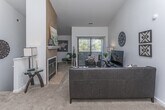Located at 2210 Metropolitan Pkwy in Sterling Heights, Michigan, this thoughtfully designed single-floor residence offers a bright and welcoming interior with a range of functional and aesthetic highlights throughout. The living room is a standout space, featuring soaring vaulted ceilings that enhance the sense of openness, plush carpeting, and a striking tile-surround fireplace that serves as a natural focal point. A sliding glass door leads to a private balcony, inviting abundant natural light and outdoor views into the living area. The dining area flows seamlessly from the living room and provides an intimate setting, accented by a large wall mirror that adds depth to the space. The galley-style kitchen is well-appointed with white cabinetry, dark granite-style countertops, stainless steel appliances, and tile flooring, with convenient in-unit laundry accessible nearby. The primary bedroom is generously sized with carpeted floors, ample natural light from multiple windows, a walk-in closet, and a private en-suite bathroom. The bathrooms are finished with white vanities, rich granite-tone countertops, tile flooring, and glass-enclosed shower options. A second full bathroom with a tub and shower combination provides added convenience for guests.