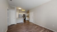 This single-floor residence offers a thoughtfully designed open-concept layout that seamlessly connects the living area and kitchen, creating a welcoming and functional space. Rich wood-style flooring flows throughout the main living areas, complemented by neutral warm-toned walls that enhance the bright, airy atmosphere provided by flush-mount ceiling lighting.

The kitchen is a standout feature, showcasing crisp white shaker cabinetry, granite countertops, and a classic subway tile backsplash. A full suite of stainless steel appliances — including a refrigerator, range, microwave, and dishwasher — adds a modern, polished touch. A peninsula with additional counter space provides both extra prep area and a natural divider between the kitchen and living room.

The bedroom offers a comfortable retreat with plush carpeting, a window with blinds that invites natural light, and a ceiling fan fixture. The bathroom is finished with the same attention to detail found throughout the unit, featuring a white vanity with granite countertop, a large framed mirror with overhead lighting, and a full tub-and-shower combination. Wood-style flooring continues into the bathroom, tying the space together cohesively. Overall, the unit presents a clean, modern aesthetic with quality finishes throughout.
