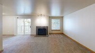 Located at Iron Mountain Lane in Bremerton, Washington, this single-floor residence offers a thoughtfully designed layout with a warm, functional aesthetic throughout. The spacious living room serves as the heart of the home, centered around a striking granite-surround fireplace that adds both elegance and coziness. Track lighting illuminates the room, which features neutral-toned carpeting and a textured ceiling. A sliding glass door opens to a private balcony, while an additional window fills the space with natural light and views of surrounding greenery.

The kitchen is efficiently designed with light maple cabinetry, granite-toned countertops, and wood-look flooring. Stainless steel appliances — including a refrigerator, electric range, and microwave — provide modern functionality, and a double-basin sink adds convenience. A dedicated pantry with open shelving offers generous storage.

The bedrooms are carpeted and well-proportioned, each featuring windows for natural light and closets with sliding panel doors. A utility area with a towel bar and laundry hookups adds to the home's practicality. Throughout the residence, warm neutral tones, consistent finishes, and a clean, open floor plan create a comfortable and inviting living environment.