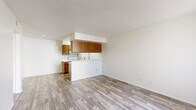 Located at 333 W Van Buren St in Avondale, AZ, this single-floor, 1-bedroom, 2-bathroom residence offers a practical and well-organized layout. The living area features wood-look plank flooring, neutral white walls, and a large window fitted with vertical blinds that allow natural light to fill the space. A textured ceiling adds a classic residential character throughout the home. The semi-open kitchen connects seamlessly to the living area via a peninsula counter with an integrated sink, providing both workspace and a visual divide. Warm-toned wood cabinetry lines the upper and lower kitchen walls, complemented by white appliances including a range and refrigerator. The bedroom is carpeted for comfort and includes a window with outdoor views, a dedicated closet, and direct access to one of the two bathrooms, which features a wood-vanity with a wide mirror and bright vanity lighting. The second bathroom includes a full tub-shower combo with clean white surroundings and brushed nickel fixtures. Wood-look flooring extends through the hallway and bathroom areas, maintaining a cohesive aesthetic. The overall ambiance is clean, neutral, and functional, making efficient use of the available space throughout.