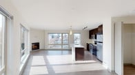 Located in Seattle's vibrant Capitol Hill neighborhood, this modern single-floor residence at 1111 East Union Street offers a thoughtfully designed open-concept layout filled with natural light. The expansive living area features light hardwood-style flooring, large floor-to-ceiling windows that frame views of the surrounding cityscape, and a sleek built-in fireplace that serves as a focal point for the space.

The contemporary kitchen is well-appointed with rich dark cabinetry extending to the ceiling, stainless steel appliances including a range, microwave, and refrigerator, and light quartz countertops. A central island with a undermount sink and pendant lighting above provides additional prep space and casual seating options.

Two carpeted bedrooms offer comfortable retreats, each with closet storage. One bedroom includes a walk-in closet with built-in shelving, while the other features a sliding-door closet. Both rooms receive generous natural light through large windows with urban views.

The residence includes two full bathrooms: one with a glass-enclosed walk-in shower and dark vanity cabinetry, and a second with a full soaking tub and shower combination, wide vanity mirror, and matching dark cabinetry. Light wood-style flooring runs throughout both bathrooms, maintaining a cohesive, modern aesthetic across the entire home.