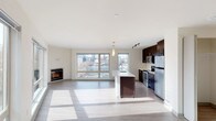 Located in Seattle's vibrant Capitol Hill neighborhood, this modern single-floor residence at 1111 East Union Street offers a thoughtfully designed open-concept layout filled with natural light. The expansive living area features light hardwood-style flooring, large floor-to-ceiling windows that frame views of the surrounding cityscape, and a sleek built-in fireplace that serves as a focal point for the space.

The contemporary kitchen is well-appointed with rich dark cabinetry extending to the ceiling, stainless steel appliances including a range, microwave, and refrigerator, and light quartz countertops. A central island with a undermount sink and pendant lighting above provides additional prep space and casual seating options.

Two carpeted bedrooms offer comfortable retreats, each with closet storage. One bedroom includes a walk-in closet with built-in shelving, while the other features a sliding-door closet. Both rooms receive generous natural light through large windows with urban views.

The residence includes two full bathrooms: one with a glass-enclosed walk-in shower and dark vanity cabinetry, and a second with a full soaking tub and shower combination, wide vanity mirror, and matching dark cabinetry. Light wood-style flooring runs throughout both bathrooms, maintaining a cohesive, modern aesthetic across the entire home.