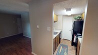 This two-floor residence offers a practical and well-organized layout designed for comfortable everyday living. The main level features an open living area with rich hardwood-style flooring, neutral-toned walls, and a front entry door with sidelight windows that invite natural light into the space. A textured ceiling runs throughout the home, adding a consistent architectural detail across all rooms.

The kitchen is efficiently arranged in a galley style, featuring warm wood cabinetry, laminate countertops, a stainless steel sink, and black appliances including a refrigerator and an electric range with overhead ventilation. A pass-through opening connects the kitchen to the main living area, creating an open and communicative flow between spaces.

The bedrooms are carpeted for comfort, with one room showcasing a wide window overlooking greenery and a ceiling fan with integrated lighting, providing both ventilation and ambiance. Additional bedrooms are generously sized with neutral walls and closet access.

A bathroom includes a wide vanity with a speckled countertop and a large mirror, with direct access to a walk-in closet area. The dedicated laundry room houses a full-sized washer and dryer, adding everyday convenience. Throughout the home, the consistent use of neutral tones, textured ceilings, and functional finishes creates a cohesive and practical living environment.