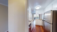 This single-floor residence offers a thoughtfully designed layout with a blend of hardwood flooring and plush carpeting throughout. The kitchen is a standout feature, equipped with white cabinetry, granite countertops, stainless steel appliances, and a peninsula that provides additional prep and dining space. Rich hardwood floors run through the kitchen and dining areas, complementing the warm, neutral tones of the walls.

The living area is generously sized, featuring crown molding, a ceiling fan, and sliding glass doors that open to an outdoor balcony, allowing for ample natural light and outdoor views. The transition from hardwood to carpet marks the entry into the living space, adding a cozy feel.

The bedrooms are carpeted and bathed in natural light through large windows and sliding glass panels that frame outdoor greenery and surrounding neighborhood views. One bedroom includes mirrored sliding closet doors, while another offers access to a walk-in closet and a private hallway connection.

The bathroom is clean and functional, featuring a granite-topped vanity with white cabinetry, a framed mirror with overhead lighting, and a tiled shower area. Overall, the space presents a comfortable and practical layout with consistent finishes throughout.