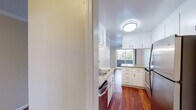 This single-floor residence offers a thoughtfully designed layout with a blend of hardwood flooring and plush carpeting throughout. The kitchen is a standout feature, equipped with white cabinetry, granite countertops, stainless steel appliances, and a peninsula that provides additional prep and dining space. Rich hardwood floors run through the kitchen and dining areas, complementing the warm, neutral tones of the walls.

The living area is generously sized, featuring crown molding, a ceiling fan, and sliding glass doors that open to an outdoor balcony, allowing for ample natural light and outdoor views. The transition from hardwood to carpet marks the entry into the living space, adding a cozy feel.

The bedrooms are carpeted and bathed in natural light through large windows and sliding glass panels that frame outdoor greenery and surrounding neighborhood views. One bedroom includes mirrored sliding closet doors, while another offers access to a walk-in closet and a private hallway connection.

The bathroom is clean and functional, featuring a granite-topped vanity with white cabinetry, a framed mirror with overhead lighting, and a tiled shower area. Overall, the space presents a comfortable and practical layout with consistent finishes throughout.