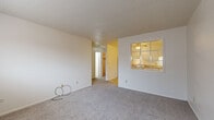 Located at 1134 Westmoreland Rd in Colorado Springs, CO, this single-floor unit offers a straightforward and functional layout designed for comfortable everyday living. The living area is carpeted and features a textured ceiling, providing a cozy feel with natural light filtering through windows. A pass-through window connects the living space to the kitchen, creating an open sightline between the two areas. The kitchen is well-equipped with white cabinetry, ample counter space, a refrigerator, electric range, dishwasher, and a sink, all set atop stone-pattern tile flooring that adds a classic touch. Adjacent to the kitchen is a dining area with the same tile flooring, complemented by built-in open shelving that adds a unique display or storage element. The bedroom is generously sized with plush carpeting, a ceiling fan, and a full-width closet with bifold doors, offering ample storage. A window in the bedroom allows natural light to brighten the room. The bathroom includes a vanity with white cabinetry and a clean tub and shower combination with chrome fixtures. A carpeted hallway connects the main rooms, contributing to the unit's cohesive and practical flow throughout.
