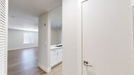 This single-story, 2-bedroom, 2-bathroom home offers a thoughtfully designed layout with clean, modern finishes throughout. The open-concept kitchen and living area serves as the heart of the home, featuring a sleek white shaker-style kitchen with floor-to-ceiling cabinetry, white quartz countertops, a stainless steel undermount sink, and a full suite of stainless steel appliances including a refrigerator, range, microwave, and dishwasher. Light wood-look flooring runs throughout the main living areas, contributing to a bright and cohesive aesthetic. The living room is bathed in natural light through windows fitted with horizontal blinds. Both bedrooms are generously sized and finished with plush carpet flooring and ceiling fans, with windows that frame views of lush greenery. Each bedroom includes its own dedicated closet. The primary bedroom is particularly spacious, with a vaulted ceiling adding an airy sense of volume. The bathrooms are finished with white shaker vanities, quartz countertops, and illuminated mirrors. One bathroom features a tub-shower combination. Throughout the home, neutral gray walls, clean white trim, and modern brushed nickel hardware create a cohesive, contemporary feel.