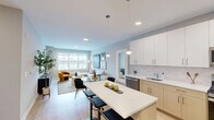 Located at 968 Bonnel Court in Union, NJ, this well-appointed one-bedroom, one-bathroom residence offers a thoughtfully designed layout across a single floor. The open-concept kitchen and living area form the heart of the home, where a sleek kitchen impresses with white upper cabinetry, warm wood lower cabinets, a white quartz waterfall island with bar seating, a subway tile backsplash, stainless steel appliances including a gas range and French door refrigerator, and globe pendant lighting. The kitchen flows seamlessly into a bright living room characterized by large windows that invite abundant natural light and views of the surrounding neighborhood. Light-toned hardwood flooring runs throughout, enhancing the airy, cohesive feel of the space. The bedroom is a comfortable retreat with a broad window framing outdoor views, neutral tones, and ample room for furnishings. The bathroom features elegant marble-look tile flooring, clean white walls, and a full tub-shower combination. A dedicated closet provides practical storage. The overall aesthetic is modern and refined, with a soft, neutral color palette of whites and light grays that creates a calm, welcoming ambiance throughout.