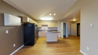 Located at 1710 13th Street SE in Minot, North Dakota, Unit 311 is a thoughtfully laid-out single-floor residence offering a functional and comfortable living environment. The kitchen serves as a focal point of the unit, featuring light maple cabinetry, dark laminate countertops, a full suite of black appliances including a refrigerator, range, microwave, and dishwasher, and a central island that provides additional prep space and casual dining potential. Durable hardwood-style flooring runs throughout the kitchen and common areas, giving the space a clean, cohesive look. A dedicated pantry or storage closet is conveniently accessible from the kitchen area. The bedrooms are carpeted and finished in warm neutral tones, each with windows that allow natural light and views of the surrounding landscape. Baseboard heating units are present in the bedrooms, ensuring year-round comfort. The bathroom includes a light maple vanity with dark countertop and an overhead lighted mirror. A dedicated laundry room with full-size side-by-side washer and dryer adds everyday convenience. A carpeted hallway connects the private areas of the unit, and a walk-in closet provides ample storage. The overall layout is practical and well-organized, suited for comfortable daily living.