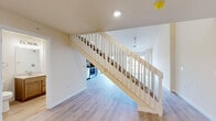 Located at 861 Kimball Lane in Verona, Wisconsin, this two-story home offers a thoughtfully designed layout spread across two floors. The main level serves as the heart of the home, encompassing an open-concept kitchen and living area. The kitchen is outfitted with warm-toned shaker-style cabinetry, stone-look countertops, stainless steel appliances including a range, microwave, and dishwasher, and stylish pendant lighting overhead. The living area flows seamlessly from the kitchen and benefits from soaring vaulted ceilings, a ceiling fan, and a sliding glass door that invites natural light and outdoor access. Light-toned hardwood-style flooring runs throughout the main level, lending a clean and cohesive aesthetic. A staircase with a white-railed banister connects the main floor to the upper level, where a generously sized room features sloped ceilings and plush carpeting, adding a cozy and versatile feel. The home includes three bathrooms, each finished with wood-toned vanities, light countertops, contemporary light fixtures, and hardwood-style flooring. Additional features include a hallway with a walk-in closet area, providing practical storage solutions. The overall design is modern, bright, and move-in ready.